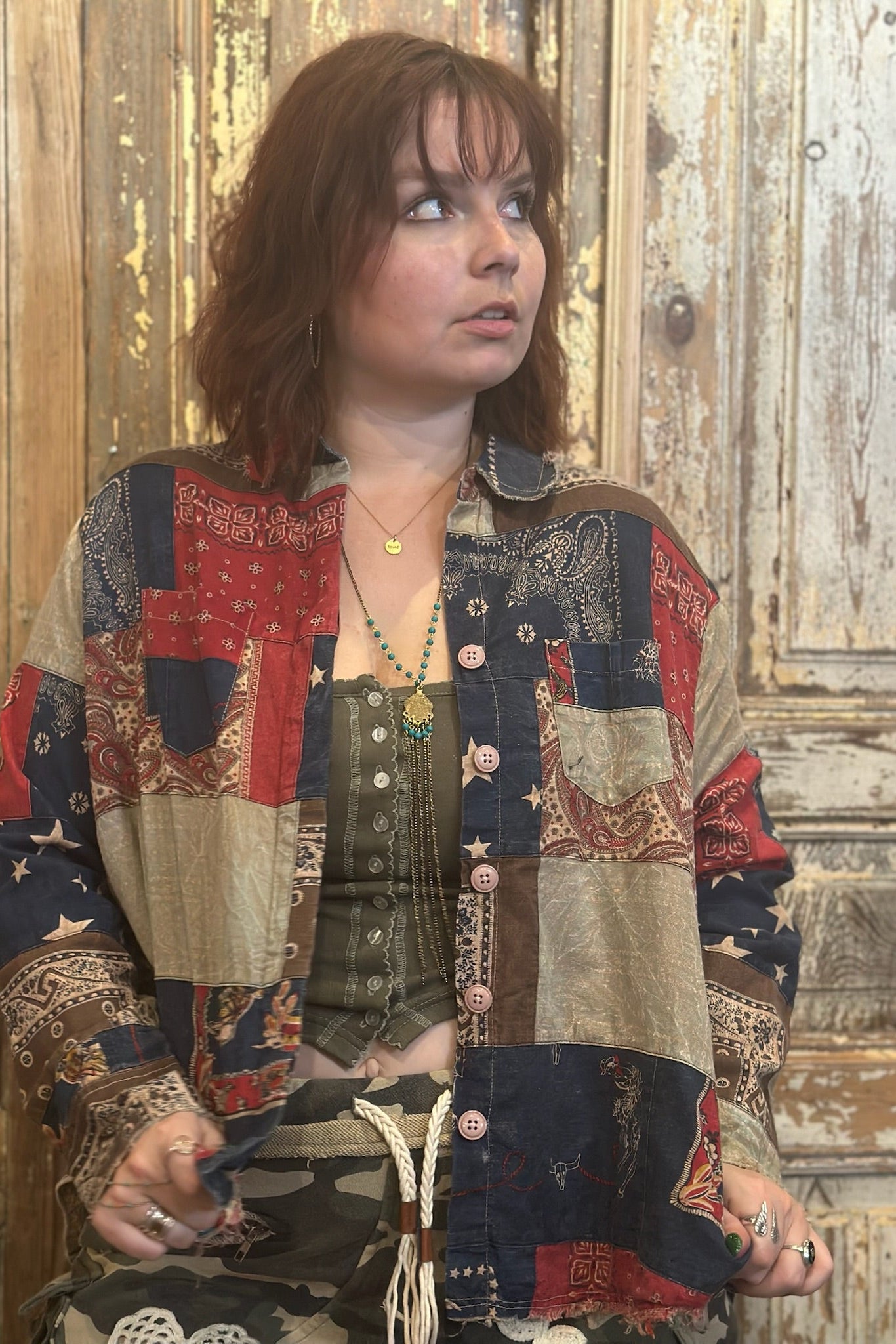 Woman wearing a patchwork jacket in a rustic setting